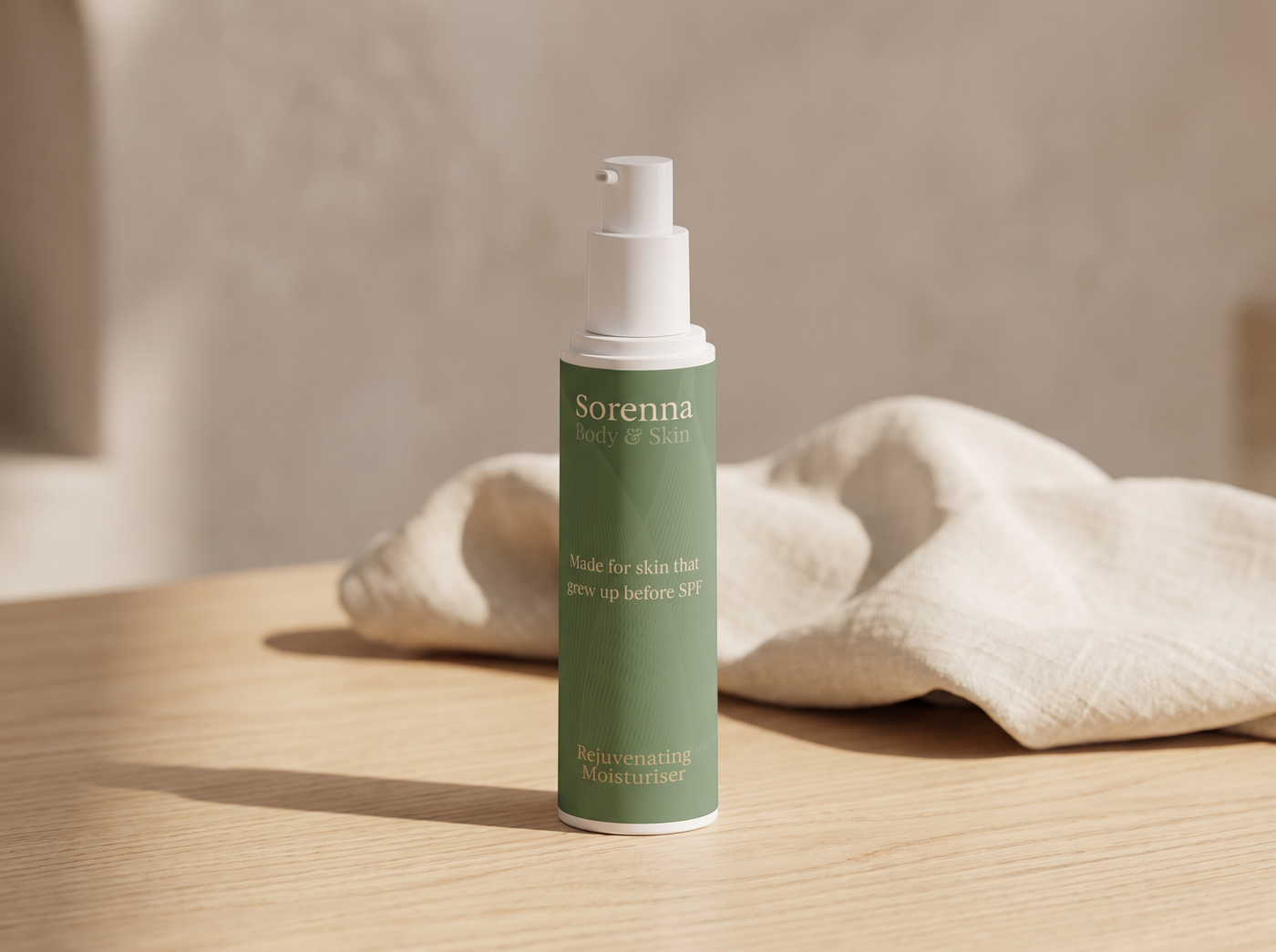 Sorenna Rejuvenating Moisturiser pump bottle standing on a wooden table with a draped linen cloth, against a plastered wall background
